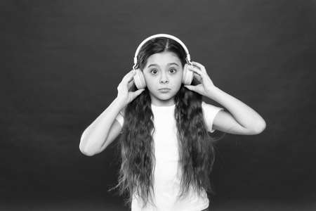 What is all this about. Small girl wearing stereo headphones. Cute music fan with wireless headset. Little child using technology for leisure or education. Little girl listening to musicの写真素材
