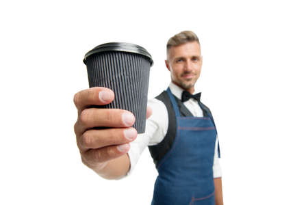 Have nice day. Take your coffee. Barista in apron served coffee. Coffee shop concept. Mature barista hold drink. Try caffeine drink. Energy recharge. Bearded man bartender hold paper coffee cupの写真素材