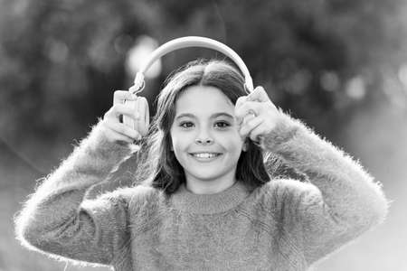 All she wants to hear is music. Adorable little girl outdoor. Little girl child wearing headphones. Happy child enjoy listening to music on the go. Having incredible sound for all her entertainmentの写真素材