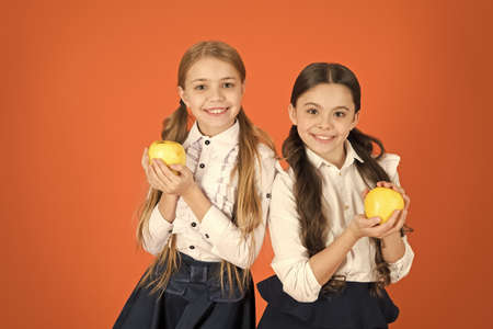Using nutrition first. Cute schoolgirls holding apples. School children with healthy apple snack. Little girls taking school snack break. Small girls eating vitamin food. Fruits are high in vitaminの写真素材