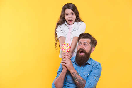 Happy family dad and daughter eat lollipop yellow background, sweet team conceptの写真素材