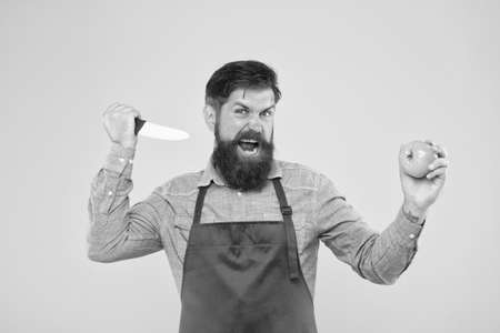 Aggression concept. Mad cook. Ultimate list of cutting techniques every chef should know. Bearded man prepare tomato. Safe cutting. Cutting veggies. Salad recipe. Mature man hold knife and vegetableの写真素材