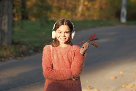 Magical moments start with music. Adorable girl enjoy music on autumn landscape. Cute little child listen to music playing in stereo headphones. Music education for small childrenの写真素材
