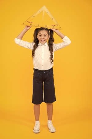 Schoolgirl school uniform hold big ruler geometry school lesson. Kid cute school student study...