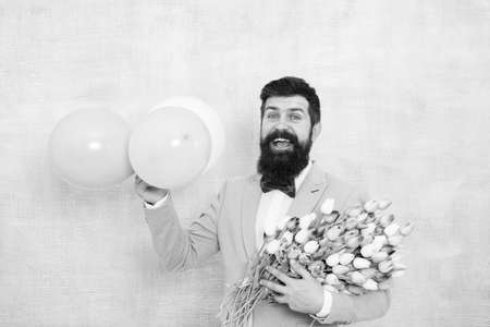 Spring party. Surprise party romantic proposal ideas. Present for spouse. Guy with air balloons. Birthday party. Bearded man hipster with flower bouquet. Womens day. Bearded man with tulipsの写真素材