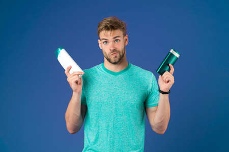 Man athlete hold shampoo bottles. Hair care. Shampoo for daily use. Skin lotion. Make choice
