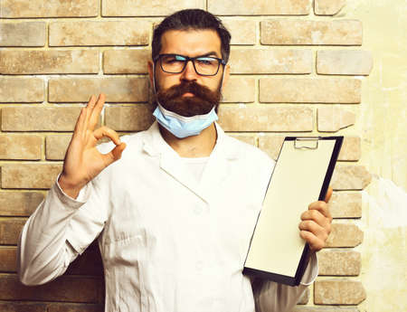 Bearded brutal caucasian doctor or postgraduate student with clipboardの写真素材