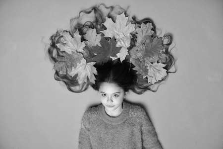 Haircare tips add to fall routine. Little girl gorgeous long hair and fallen maple leaves. Deep...