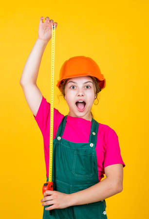 Cute kid as a construction worker. kid repairing home. happy childhood. self-retracting metal tape measure. Little girl using a measuring tape. construction worker with tape measureの写真素材