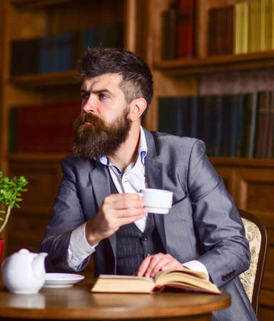 businessman sitting in cafe and drinking tea while reading book