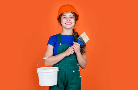 Girl in a protective helmet holds the paintbrush. childhood and people concept. teen kid ready for painting. girl in protective helmet with paint brush. Child care developmentの写真素材