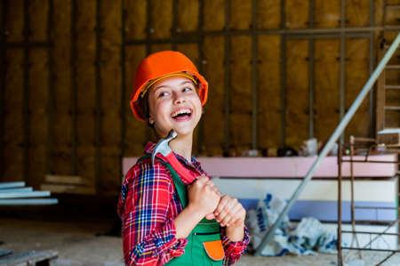 occupation learning concept. kid in workshop training to use hand instrument. girl wearing engineer...