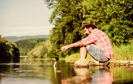 fly fish hobby. Summer activity. mature bearded man with fish on rod. hipster fishing with spoon-bait. The Old Man and the Sea. successful fisherman in lake water. big game fishing. relax on natureの写真素材