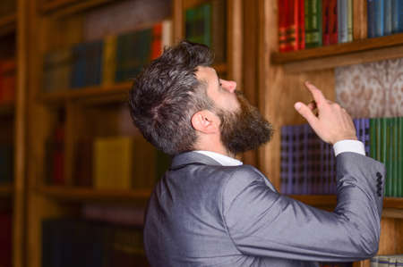 Library and books concept. Bearded man standing in modern library