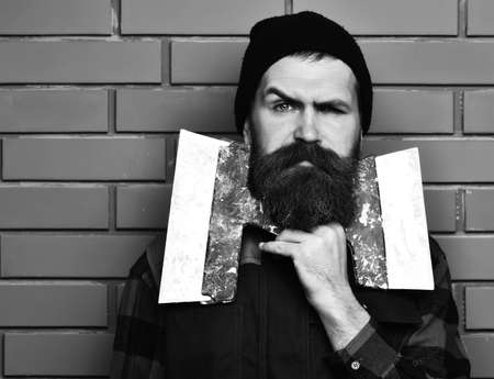 bearded worker man holding spatulas with serious faceの写真素材