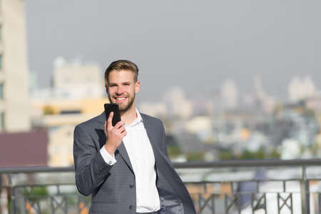 Businessman happy smiling use smartphone for video call or texting, skyline background. Man in suit businessman takes advantages of modern mobile technologies for business. Business call conceptの写真素材