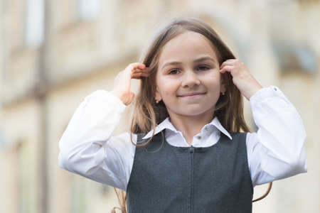Happy kid in fashion uniform with back to school look fix long hair outdoors, beautyの写真素材