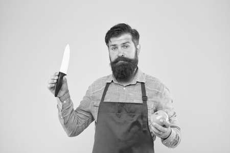 Cooking. professional chef in red apron. cooking is his hobby. bearded man in cook uniform. confident male housekeeper prepare tomato. mature man hold knife and vegetable. making fresh saladの写真素材
