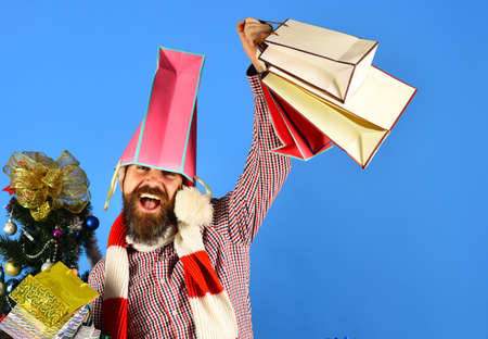 Hipster with pink packet on head holds shopping bags.の写真素材