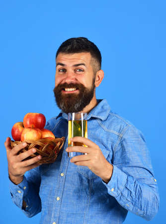 Farmer with cheerful face holds fresh apple juice and apples.の写真素材