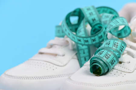 Sneakers with measuring tape on cyan backgroundの写真素材