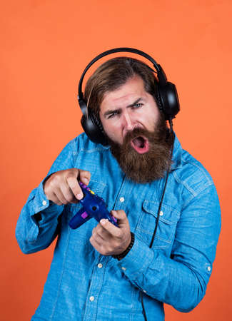 Playing is a new Skill. computer gaming concept. playing online. relax with favorite hobby. bearded man gamer. cheerful man wear modern earphones. male in headphones with game consoleの写真素材