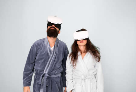 Bearded man and woman in robe. Couple in love. Family. Virtual reality and 3d. Love. modern family in vr glasses. 3d glasses. 3d technology. family couple in 3d glasses. vr headset. different realityの写真素材