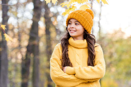 girl in yellow knitted sweater and hat. kid enjoy nature in autumn park. fall is a time for fun. fall fashion for kids. autumn style of child. knitwear warm you in any weatherの写真素材