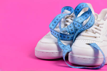 Sneakers with measuring tape on pink backgroundの写真素材