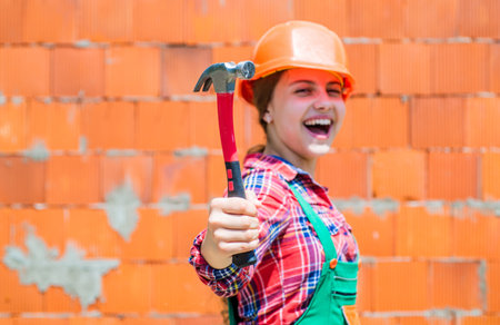 cheerful kid in helmet hold hammer. carpentry and woodworking concept. teen child using hammer tool....