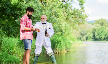 Men relaxing nature background. Fun and relax. Weekend time. Bearded man and elegant businessman fishing together. Fishing skills. Set up rod with hook line and sinker. Fishing and drinking beerの写真素材