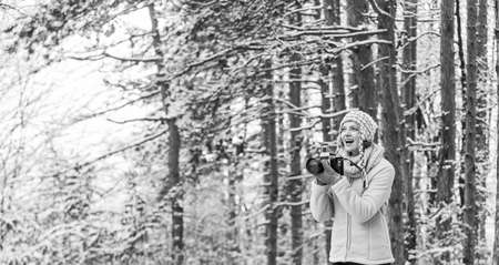 Feeling warm and happy. hobby time outdoor in winter day. admiring winter mountain landscape. Happy tourist woman in winter. professional photographer outdoor in winter. woman use vintage cameraの写真素材