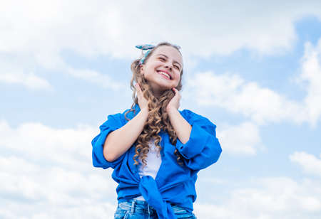 happy childrens day. happy childhood. smiling child with curly hairstyle. hair beauty and care. kid fashion style. teenage girl on sky background outdoor. hipster kid. Facial careの写真素材