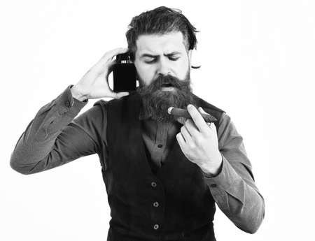 bearded man smoking cigar with serious face, holding perfumeの写真素材