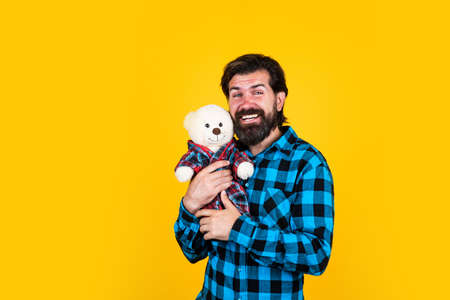 Man hold teddy bear soft toy as a present to his girlfriend for birthday party on yellow background, happy birthdayの写真素材