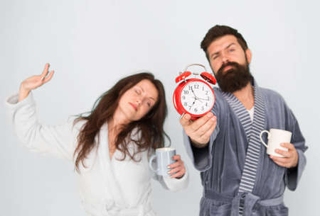 Man with beard and sleepy woman enjoy morning coffee or tea. Guy in bath clothes hold tea coffee....
