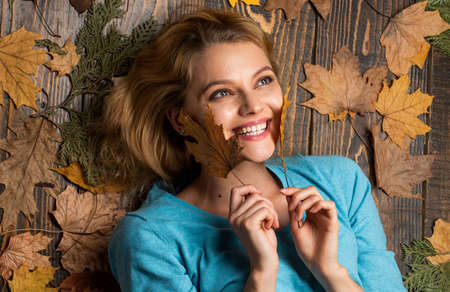 Autumn leaves and nature. Excited fall woman. girl enjoying life and freedom. season of shopping sale. Autumn leaves in girl hands. playing in autumn nature. happy woman lying on fall backgroundの写真素材