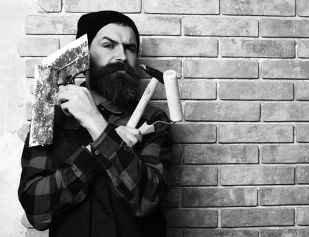 bearded painter man holding various building tools with serious faceの写真素材
