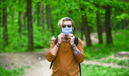man wear protective respirator mask outdoor. walk in medical mask in forest. Preventive methods from...