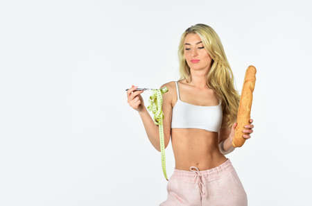 sport and fitness. healthy eating lifestyle. athletic woman isolated on white. girl in sportswear with tape measure on fork. bread against diet. fit girl with slim body shapesの写真素材
