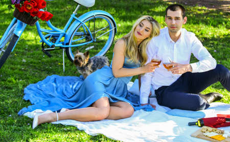 Inspiring feelings. Cute couple drinking wine picnic. Romance concept. Cheers. Celebrate anniversary. Attractive Couple Enjoying Romantic Sunset Picnic in Countryside. Couple drinking wine sunny dayの写真素材