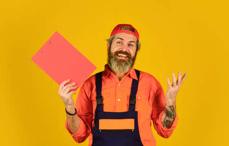 Bearded storekeeper. Supplier of goods. Delivery man in cap holding clipboard looking information. Check list. Control concept. Courier with document. Waybill or delivery note. Delivery serviceの写真素材