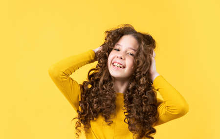 Freedom self expression. Girl hairdresser salon. Brushing long hair. Little child curly hair. Fashion and beauty. Enjoying shiny curls. Hairstyle party. Hairdresser supplies. Professional cosmeticsの写真素材