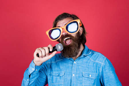 Bring music to life. performer having fun. mature bearded man in funny party glasses sing song. brutal male hipster with microphone. vocal school. favorite music styleの写真素材