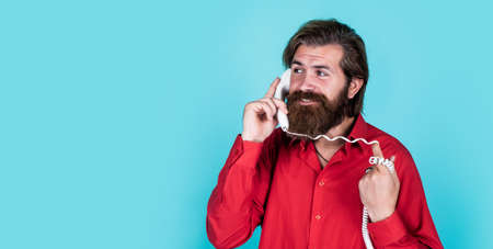 concept of communication. bearded man answer the call. handsome man has conversation. mature hipster with beard with retro phone. brutal caucasian guy speak on telephone. copy spaceの写真素材