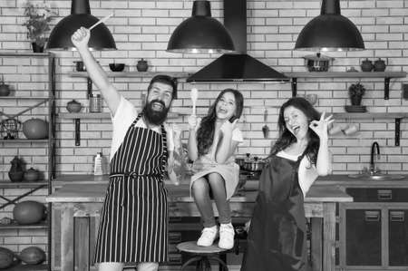 Just for fun. Family holidays. Mother father and daughter cooking together. Happy child with parents cooking in kitchen. Family preparation food. Tasks and duties. Cooking team. Cook with loveの写真素材