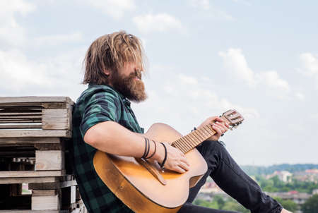 time to relax. bearded man in checkered shirt sing song. music performer musician. musical string instrument. mature charismatic male guitarist. guy with beard and moustache play guitarの写真素材