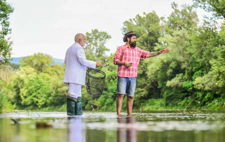Fish with companion who help in emergency. Bearded man elegant businessman fish together. Learn to fish. Expert fisherman. Men friends relaxing river background. Personal instructor. Fishing skillsの写真素材