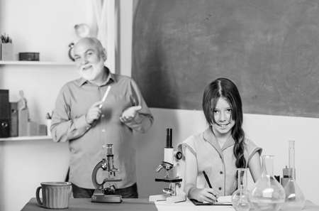 Teacher help schoolgirl. School lesson. Good pedagogue friendly kind. Little girl with man tutor study science. Pedagogue career. Experienced pedagogue. Expand your mind. Chemistry and biologyの写真素材