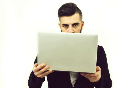 Successful businessman with serious look holds white laptopの写真素材